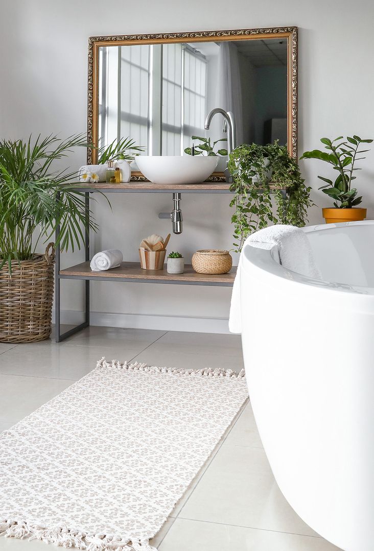 Badezimmer mit einer weißen Badewanne und einer Pflanze auf dem Boden.